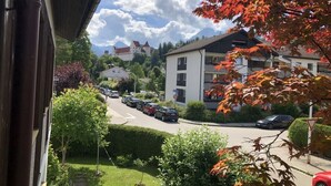A residential street with parked cars, a building with a white facade, and autumn foliage. - Family Apartment Bavaria (Fuessen)