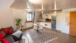 Een moderne woonkamer met een bank, een kleine tafel en een potplant.