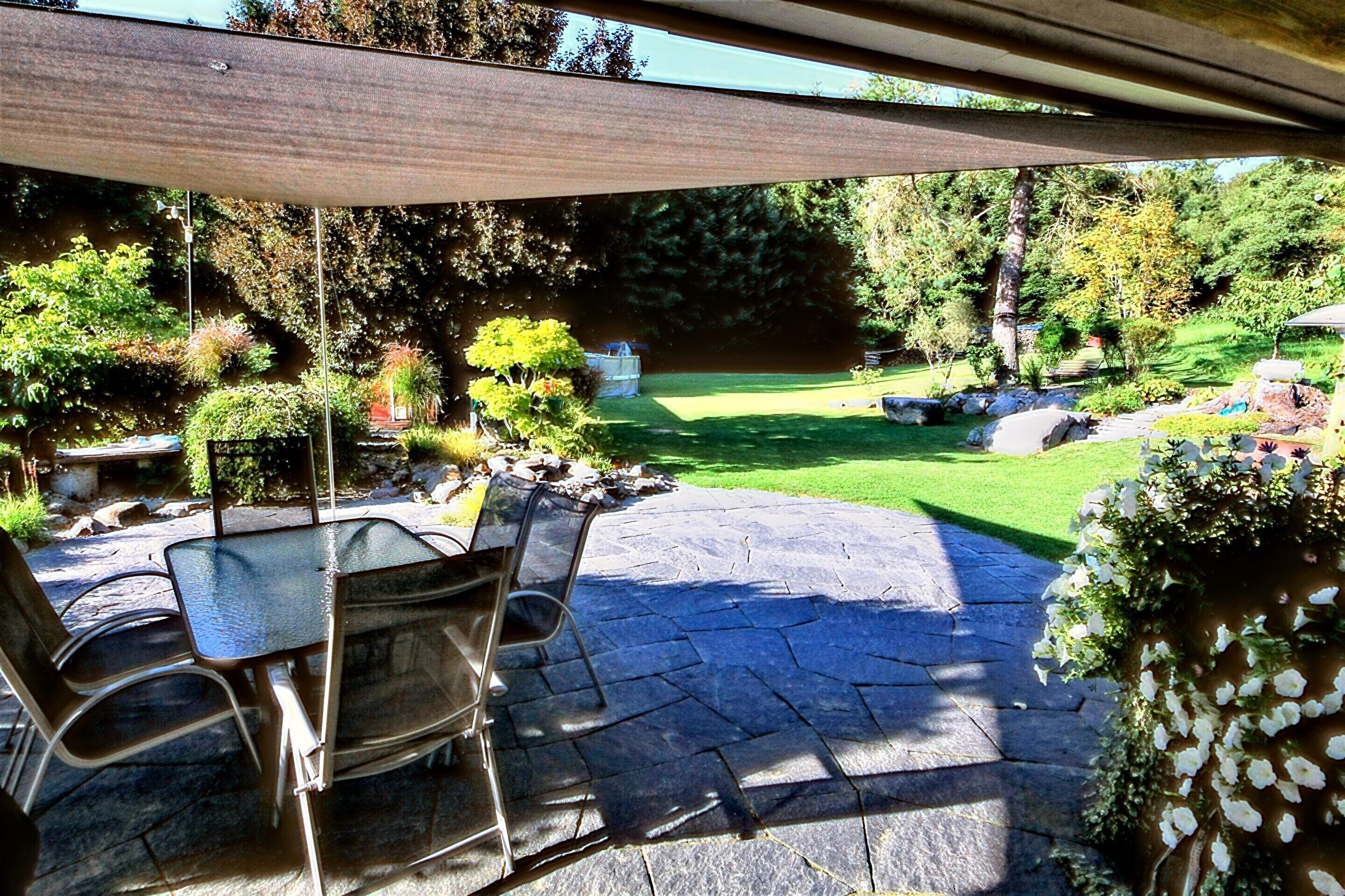 An outdoor patio area with stone flooring, metal chairs, and a covered section.