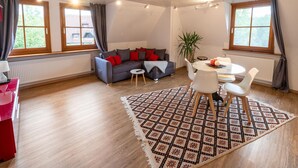 Een moderne woonkamer met een bank, eettafel, stoelen en een kamerkleed met een patroon.