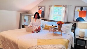 Ein Schlafzimmer mit einem Bett, einem Laptop, einer Blumenvase und einem Nachttisch mit Lampe.