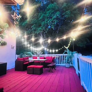 An outdoor deck with red seating, string lights, and a white railing.