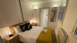 Ein Hotelzimmer mit Bett, Nachttischen, Spiegel, Fenster und Heizkörper.