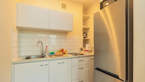 Une cuisine moderne avec des meubles blancs, un réfrigérateur en acier inoxydable et un évier.