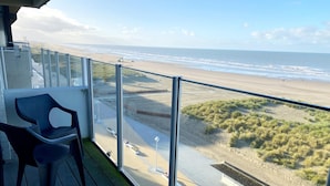 A balcony with a view of the beach, a chair, and a small garden area. - Apartment in Nieuwpoort by the Beach (Nieuwpoort)