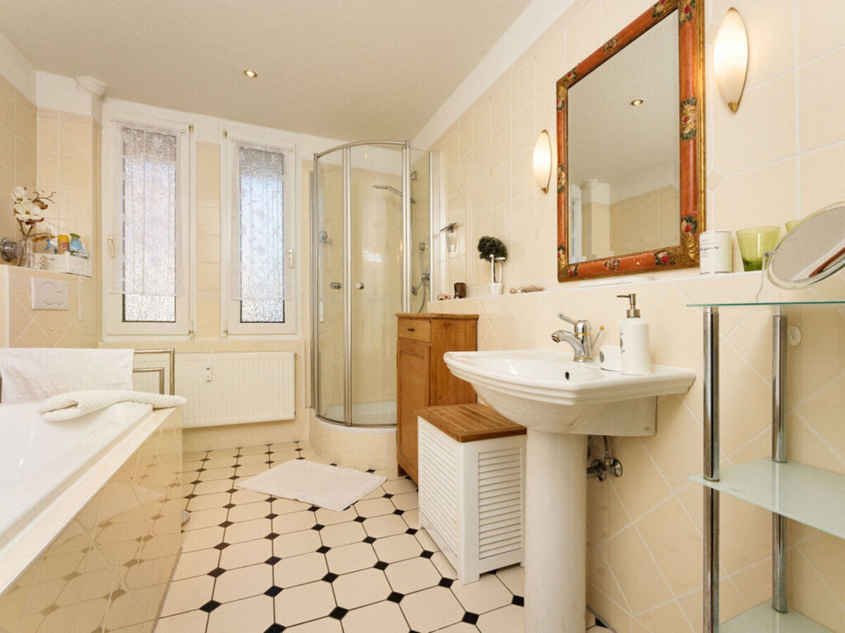 Un baño con cabina de ducha de vidrio, un lavabo blanco y un espejo grande.