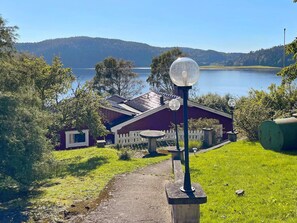 A lakeside property with a pathway leading to a building, a lamp post, and a view of the lake and hills. - 4 Star Holiday Home in Uddevalla (Uddevalla)