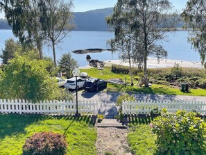 A lakeside property with a white picket fence, parked cars, and a boat dock. - 4 Star Holiday Home in Uddevalla (Uddevalla)