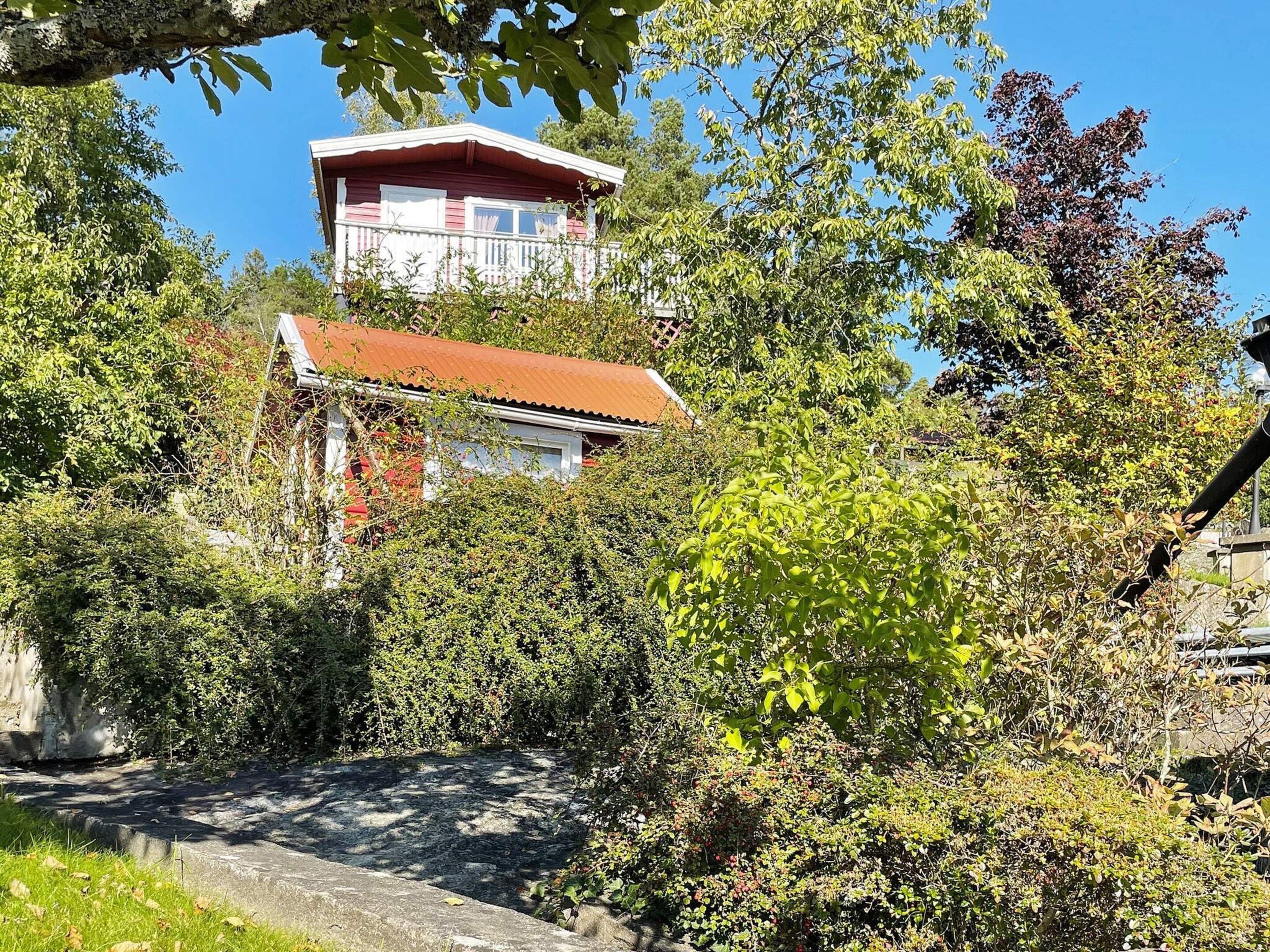 A building with a red roof and white walls, surrounded by dense greenery and trees.