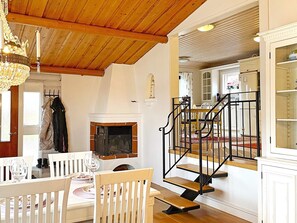A dining area with a wooden ceiling, a fireplace, and a staircase with black railings. - 4 Star Holiday Home in Uddevalla (Uddevalla)