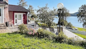 Une propriété située au bord d’un lac, avec un bâtiment en briques rouges, des sièges extérieurs et un lampadaire.
