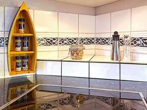 A kitchen with a black countertop, a wooden spice rack, a glass jar, and a stainless steel appliance. - 4 Star Holiday Home in Uddevalla (Uddevalla)