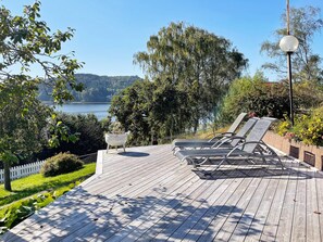 A wooden deck with lounge chairs overlooking a lake. - 4 Star Holiday Home in Uddevalla (Uddevalla)