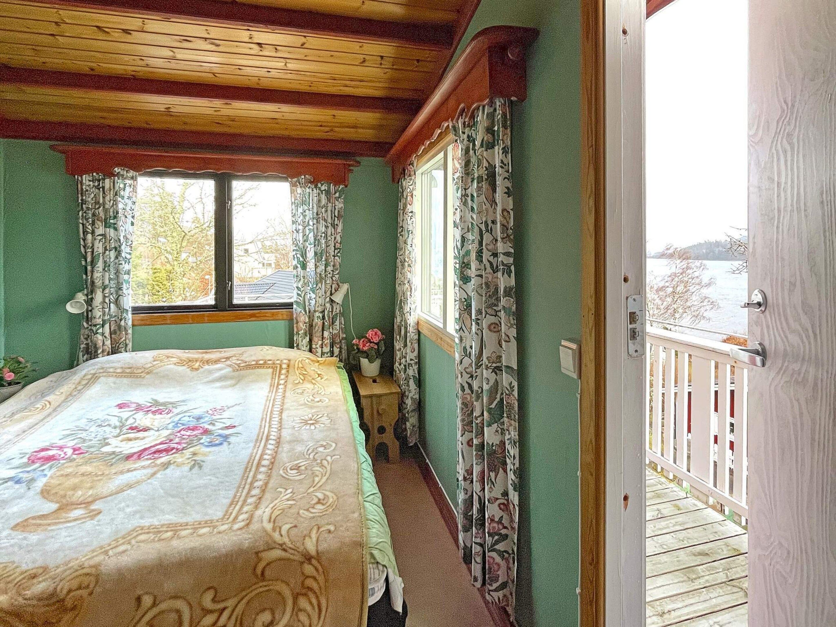 Een slaapkamer met een bed, een raam en uitzicht op een balkon.