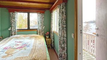 A bedroom with a bed, a window, and a view of a balcony.