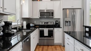 A modern kitchen with white cabinets, stainless steel appliances, and black countertops. - Asheville`s 5 Star Club!  We Invite You To See What All The Fuss Is About! (Asheville)