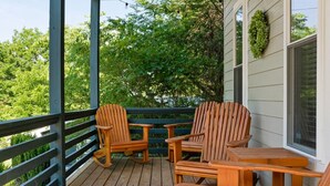 A wooden deck with Adirondack chairs and a small table, overlooking a lush green landscape. - Asheville`s 5 Star Club!  We Invite You To See What All The Fuss Is About! (Asheville)