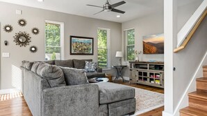 A modern living room with a grey sectional sofa, a wooden floor, and a staircase. - Asheville`s 5 Star Club!  We Invite You To See What All The Fuss Is About! (Asheville)
