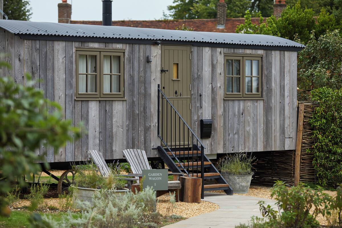 A wooden cabin with a door, windows, and a staircase leading to the entrance.