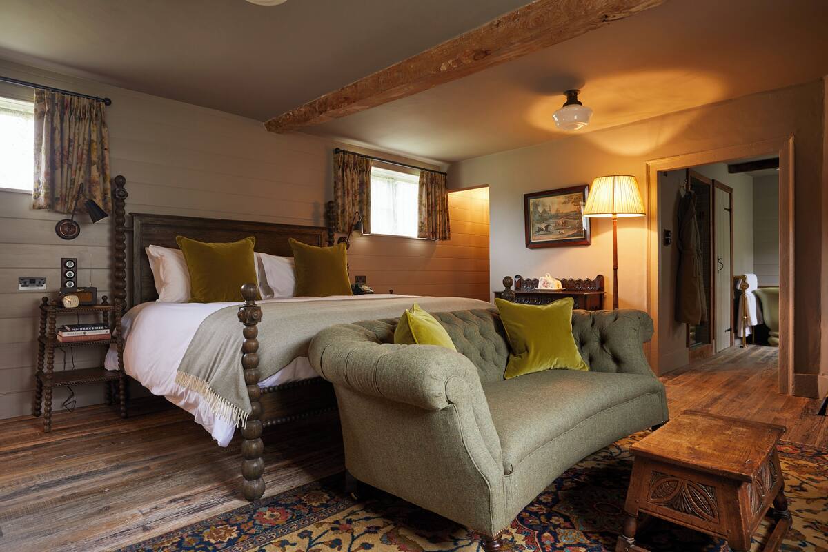 A traditional room with a bed, a sofa, a wooden floor, and a lamp.