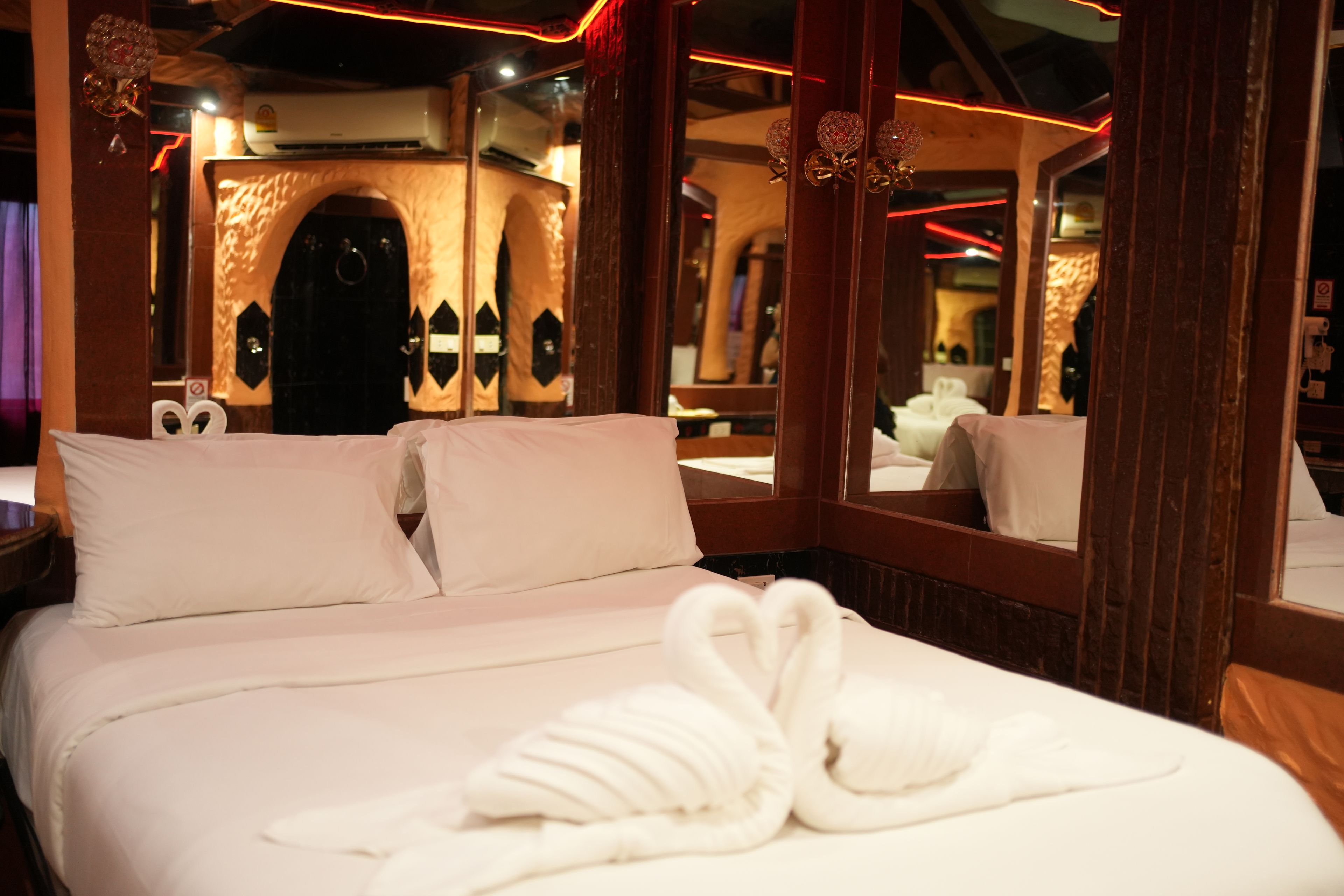 A hotel room with a large bed, a mirror, and a wall-mounted air conditioner.
