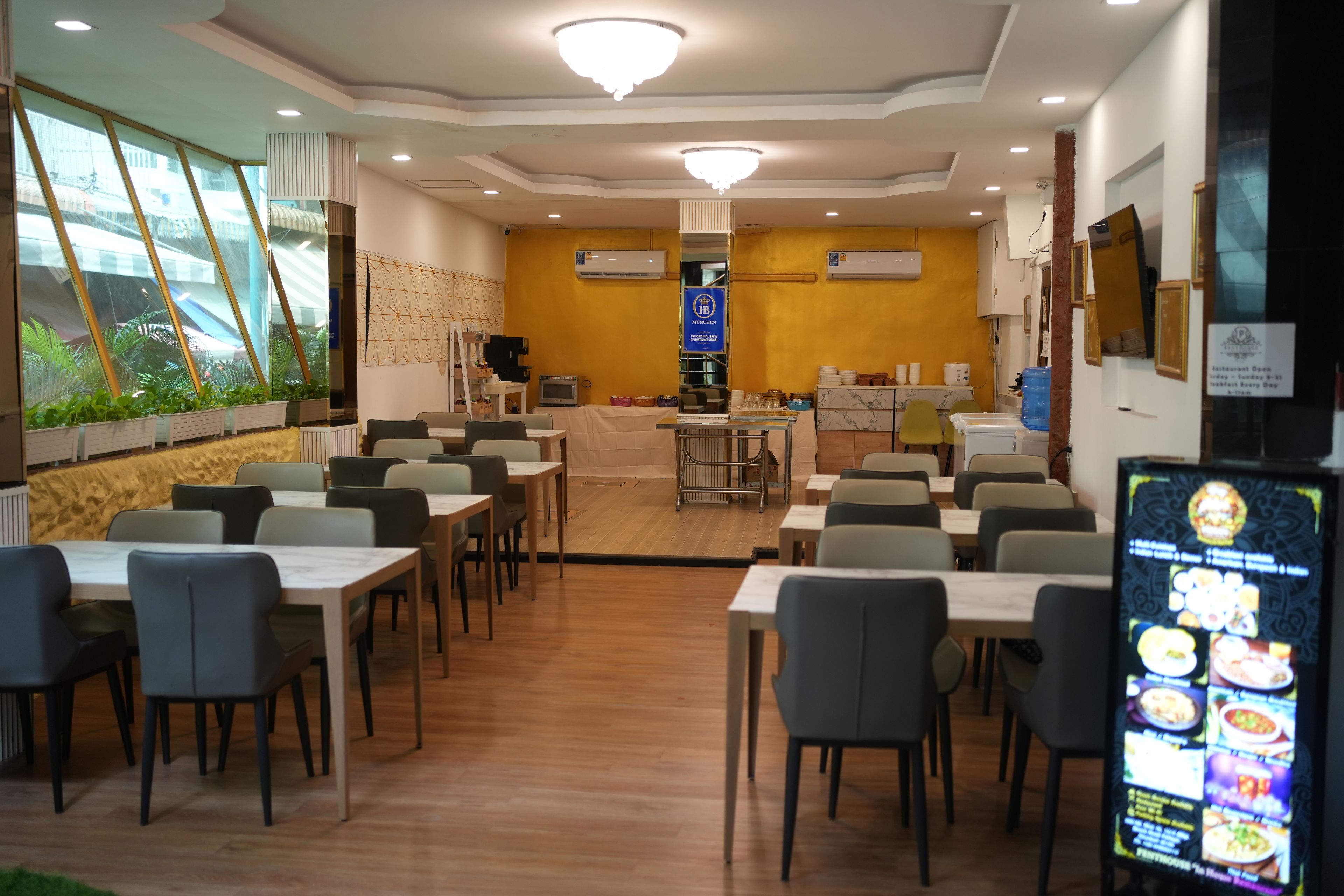 Un restaurant doté de nombreuses tables et chaises, d’un espace central pour le service et d’un présentoir pour afficher le menu.