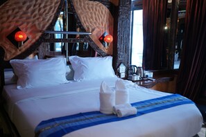A hotel room with a large bed, two pillows, a bedside table with a lamp, and a window with curtains. - Penthouse Pattaya (Pattaya)