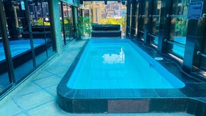 Una piscina con bordo piastrellato, circondata da porte e finestre in vetro.
