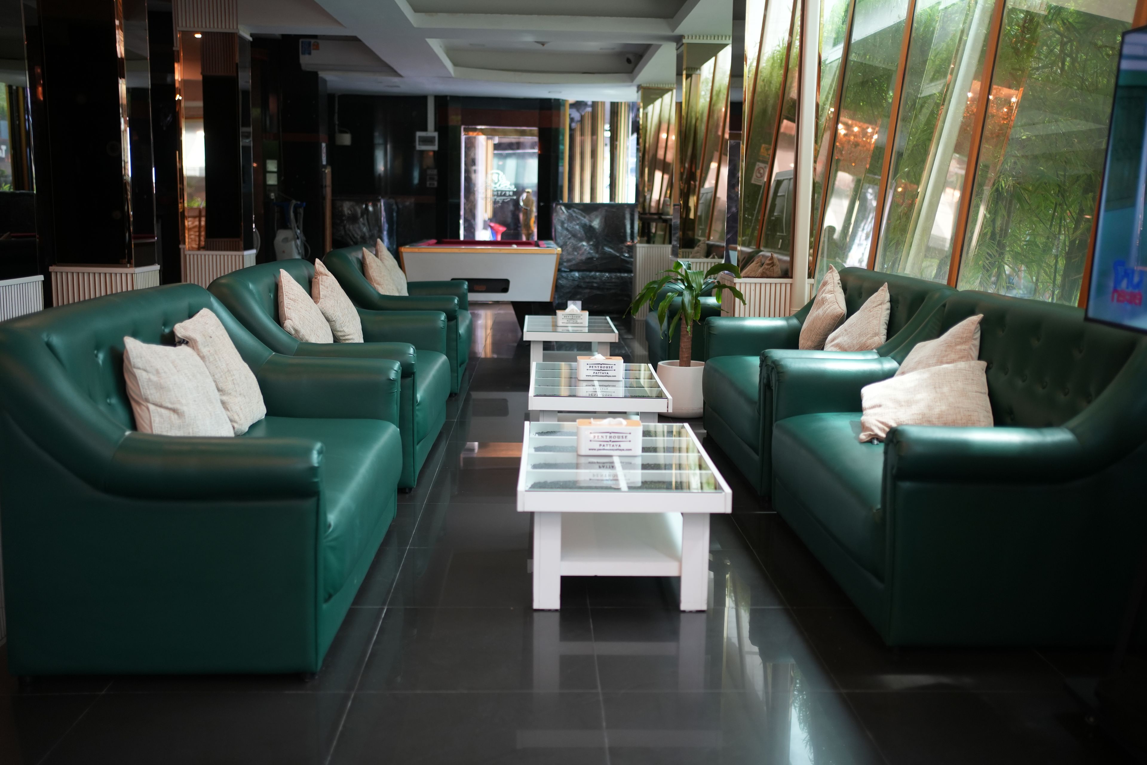 A lobby with green sofas, a coffee table, and a reception desk.