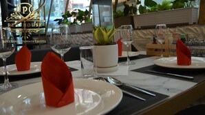 Tavola imbandita con piatti, bicchieri e un vaso di fiori.