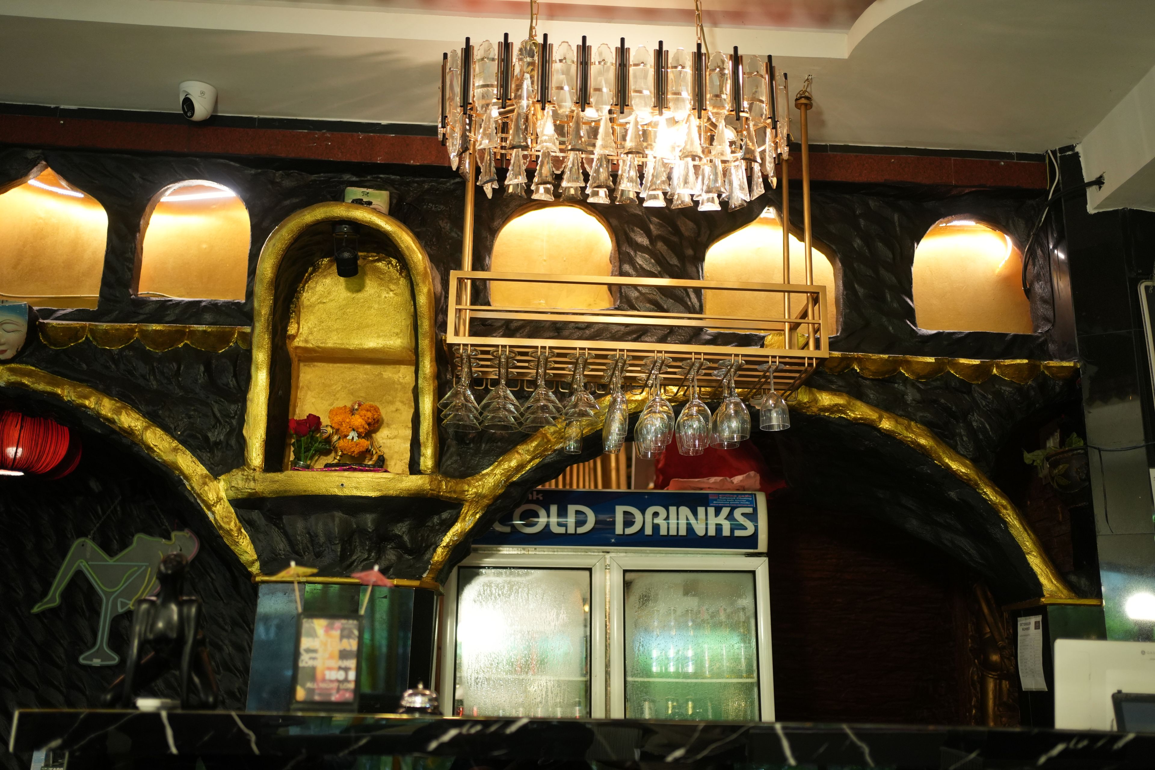 A bar area with a chandelier, a sign for 'OLD DRINKS', and a counter with glasses.
