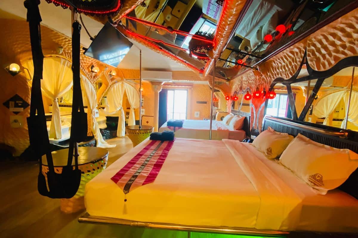 A room with a bed, a hanging chair, and a window.