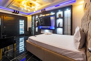 Ein modernes Hotelzimmer mit einem großen Bett, einem Flachbildfernseher und einer eingebauten Ablage mit Dekoration.
