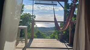 A wooden deck with a hammock, a table, and a view of a coastal landscape. - Charm and tranquility, panoramic views of the sea and the islands, 3 minutes from the beaches (porticcio)