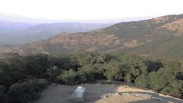Eine gebirgige Landschaft mit dichtem Wald und einem kleinen Gebäude mit Metallbedachung.