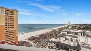 Paesaggio costiero con spiaggia, molo e un hotel di grattacielo.