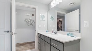 A modern bathroom with a double sink vanity, a large mirror, and a decorative wall piece. - Calypso 3-1606 Spectacular condo! Affordable rates! Inquire for details! (Panama City Beach)