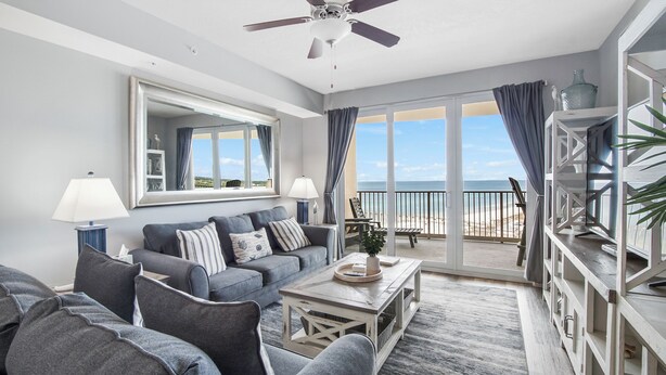 Un soggiorno moderno con divano, tavolino e un balcone vista spiaggia.
