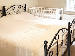 A bed with a white mattress and a black metal frame in a room with a white crib and a window. - 4 Person Holiday Home in Enviken (Enviken)