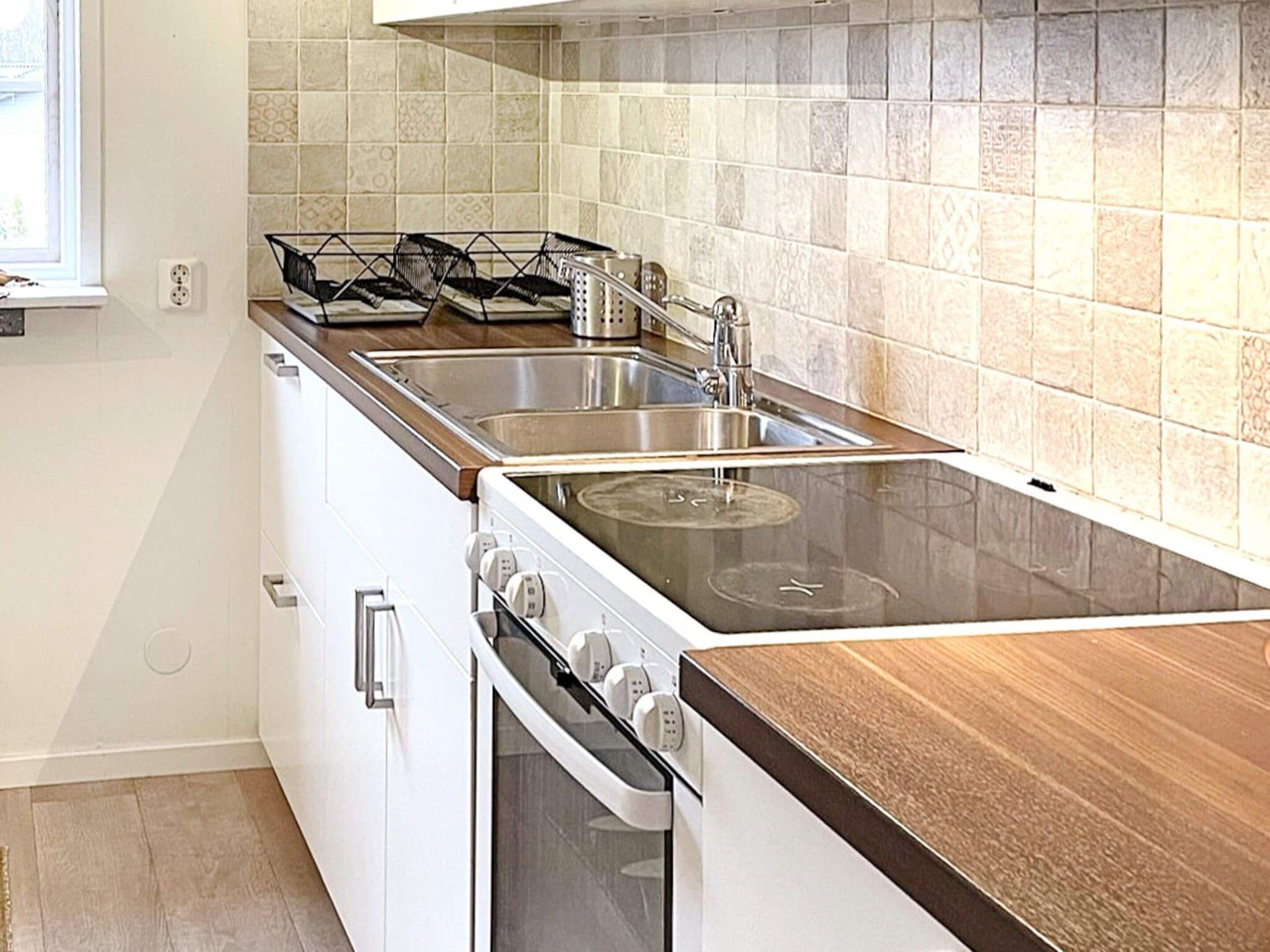Una cocina con estufa, horno y lavamanos.