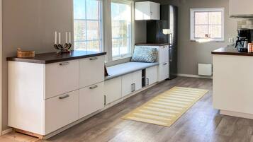 A modern kitchen with a built-in bench, large windows, and a coffee maker.