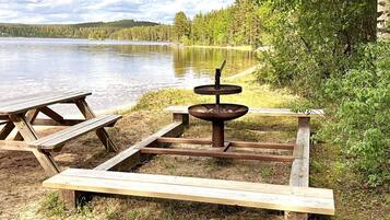 Ein Picknickplatz am Seeufer mit einer Holzbank, einem Picknicktisch und einer Feuerstelle.