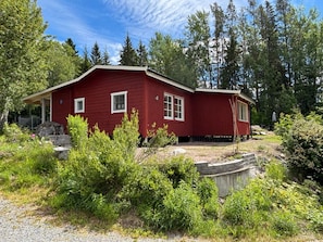 A red wooden cabin with a porch, surrounded by dense greenery and trees. - 4 Person Holiday Home in Enviken (Enviken)