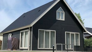 A modern two-story house with a dark exterior, large windows, and a steeply pitched roof. - Holiday Home on the Recreational Lake (Lathum)