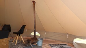 Interior de una tienda de campaña con un hornillo portátil, una silla, una mesa y una alfombra.
