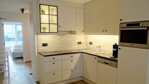 Eine moderne Küche mit weißen Schränken, einer schwarzen Arbeitsplatte und einem eingebauten Backofen.