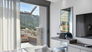 Una habitación de hotel moderna con balcón, un espejo grande, un televisor de pantalla plana y toallas dobladas con cuidado.