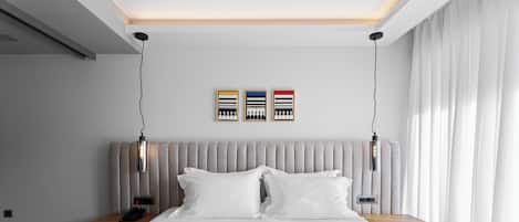 A modern hotel room with a large bed, a bedside table with a phone, and a wall-mounted light fixture.