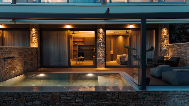 Una casa moderna con piscina, muros de piedra e interior bien iluminado.