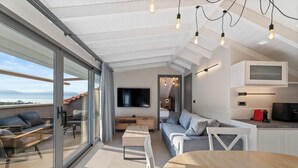 Un interior moderno con zona de comedor, sofá y televisor montado en la pared.